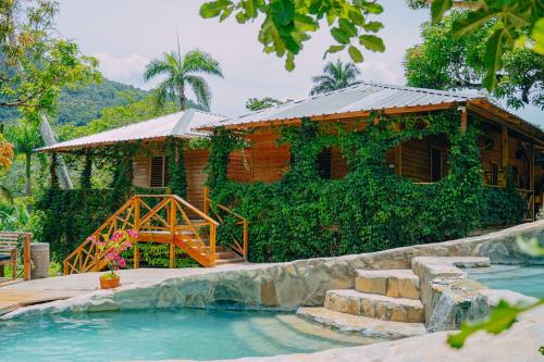 une maison en bois avec une piscine en face de celle-ci dans l'établissement EL GALLO ECOLODGE, à San Felipe de Puerto Plata