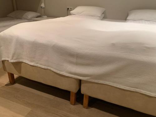 a large bed with a white blanket on it at Seydisfjördur Guesthouse in Seyðisfjörður