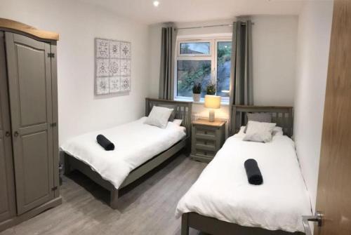a bedroom with two beds and a window at Ella Court Devon in Torquay