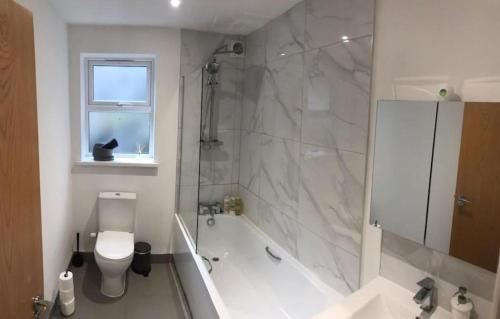 a bathroom with a tub and a toilet and a shower at Ella Court Devon in Torquay