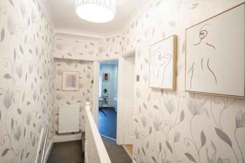 a hallway with white walls with leafy wallpaper at Air Host and Stay - Stanley Park House, 2 mins from LFC, sleeps 7 in Liverpool