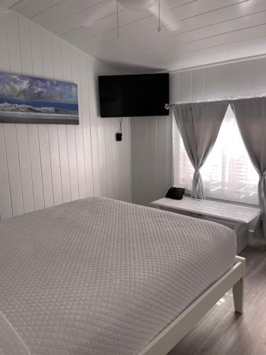a bedroom with a bed and a tv on the wall at The Palms Hotel in Key West