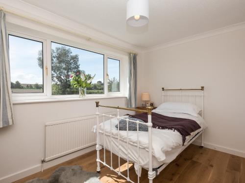 a bedroom with a bed and two windows at Crinkum in Titchwell
