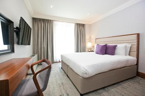 a hotel room with a large bed with purple pillows at Sanctum Maida Vale in London