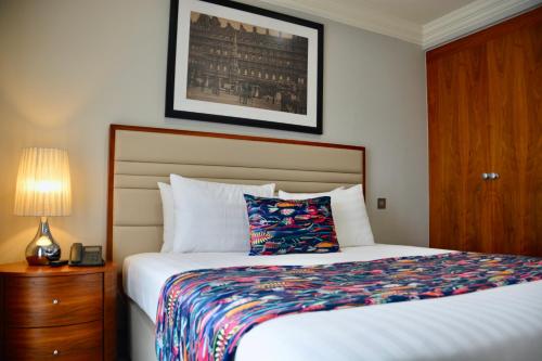a bedroom with a bed and a night stand with a lamp at Sanctum Maida Vale in London