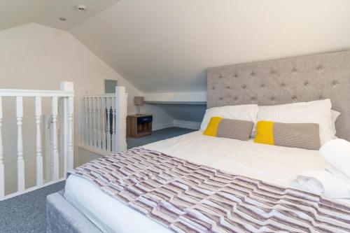 a bedroom with a large white bed with yellow pillows at York Deluxe Apartments in York