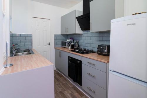 a kitchen with white cabinets and a white refrigerator at York Deluxe Apartments in York