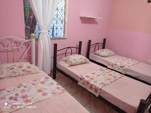 Duas camas num quarto com paredes cor-de-rosa e uma janela em Brazil Inn Hostel em Salvador