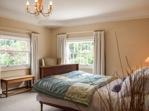 a bedroom with a bed and a chandelier and two windows at 1 Severn Bank in Ironbridge