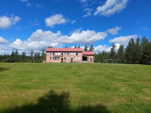 a large building in a field with a field of grass at Nederhögen Vildmarkscenter in Rätan