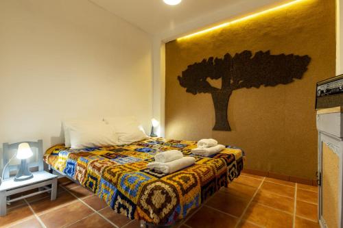 1 dormitorio con 1 cama con un árbol en la pared en Casa do Corticeiro, en Arraiolos