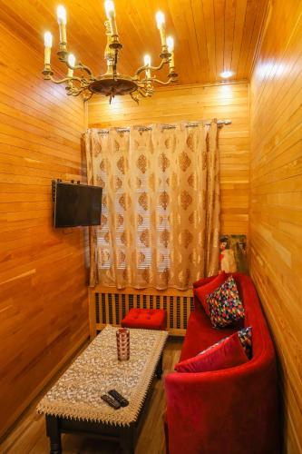 a living room with a red couch and a table at Hôtel les truites in Imouzzer Kandar