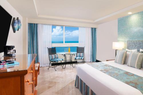 a hotel room with a bed and a table and chairs at The Sens Cancun by Oasis - All Inclusive in Cancún