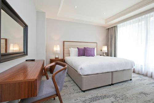 a hotel room with a bed and a desk and a desk at Sanctum Maida Vale in London