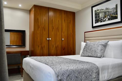 a bedroom with a bed and a wooden cabinet at Sanctum Maida Vale in London