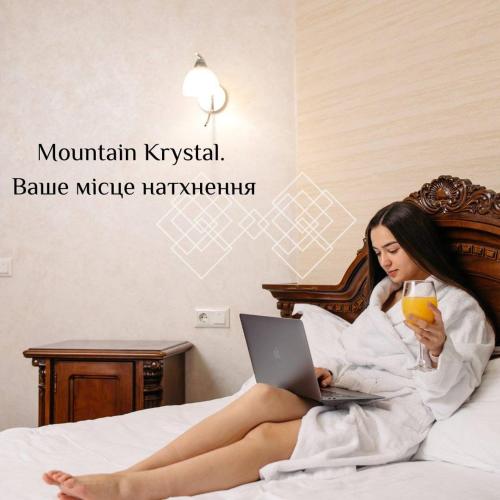 a woman laying in bed with a laptop and a drink at Mountain Krystal in Bukovel