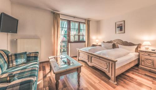 シュタイネンにあるBoutique Wellnesshotel Landmannのベッドルーム1室(ベッド1台、ソファ、椅子付)