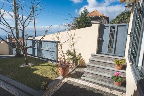 Una casa con una puerta y escaleras con plantas en macetas. en Casa da Caixeira, en Arco da Calheta