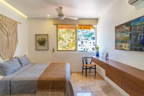 a bedroom with a bed and a desk and a window at Tres Marias Luxury Suites - Adults Only in Puerto Vallarta