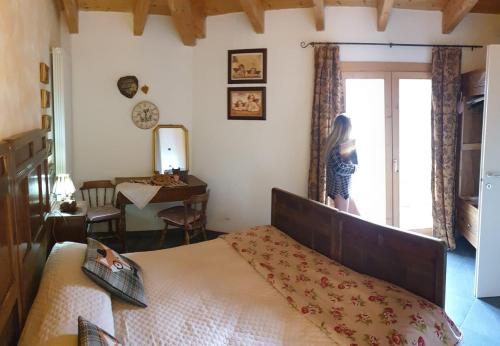 a woman standing in a bedroom looking out the window at Villa Amaranta Room and Breakfast in Edolo