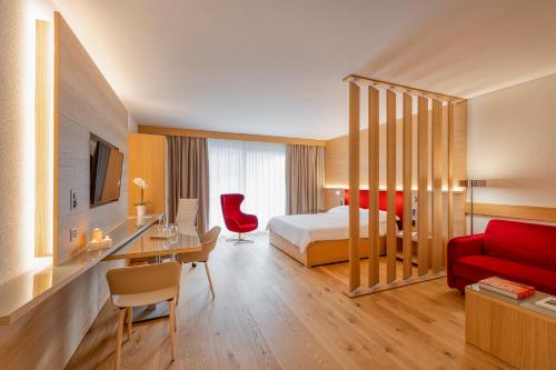 a hotel room with a bed and a red couch at NEW OPENING 2022 - Los Lorentes Hotel Bern City in Bern