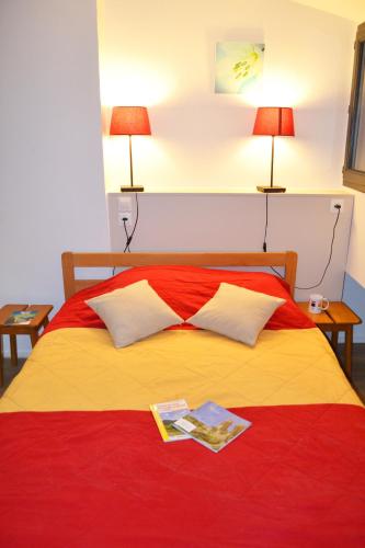 un lit avec une couverture rouge et jaune et deux lampes dans l'établissement VVF Haute Loire Saint-Julien-Chapteuil, à Saint-Julien-Chapteuil