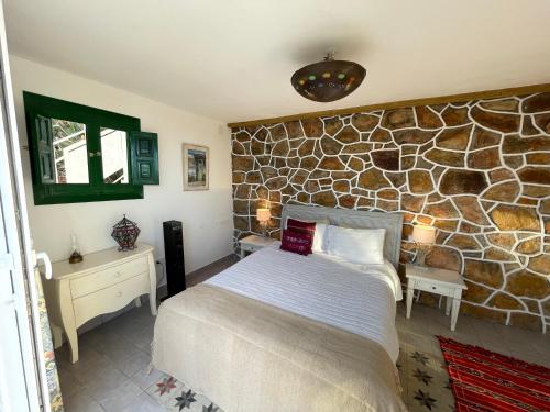 a bedroom with a bed and a stone wall at Villa Marver in Algeciras