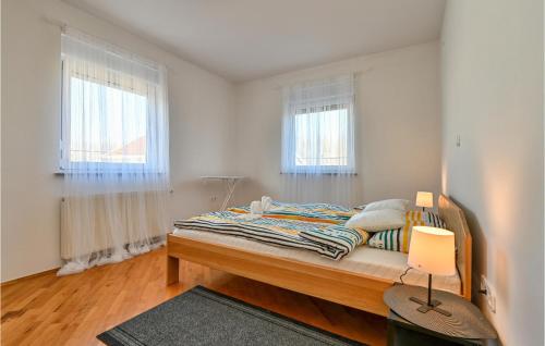 a bedroom with a bed and two windows at Lovely Home In Senkovec With Sauna in Slakovec