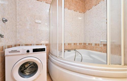 a bathroom with a washing machine and a bath tub at Stunning Home In Senkovec With Sauna in Slakovec