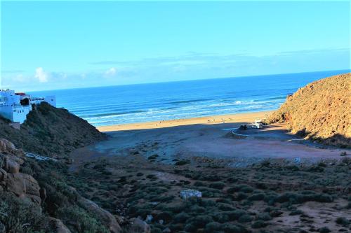a beach with a group of people on the sand at Asunfou : Appartement d'apaisement in Mirleft