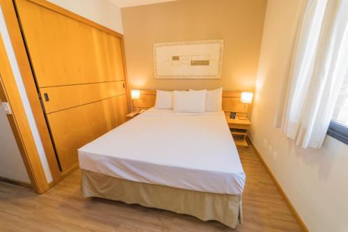 a small bedroom with a white bed and a window at Hampton Park São Paulo Jardins in Sao Paulo
