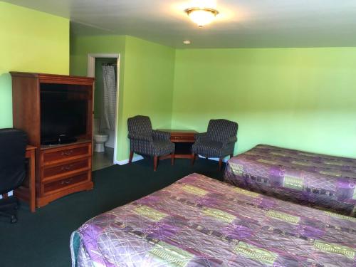 Habitación de hotel con 2 camas, escritorio y TV. en Ranch House Motel Marksville, en Marksville