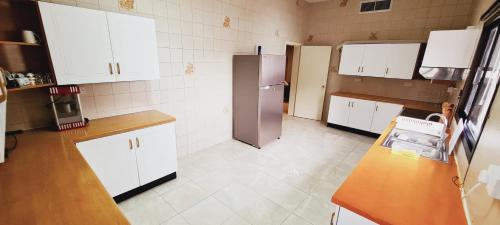 a kitchen with white cabinets and a stainless steel refrigerator at Luxury holiday villas in Bahrain for Families in Bārbār