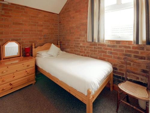 1 dormitorio con cama y pared de ladrillo en Yarlington Mill, en Ledbury