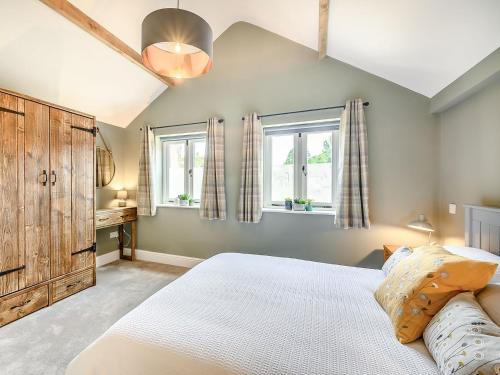 a bedroom with a large bed and two windows at The Cow Shed - Uk38575 in Aston Cantlow