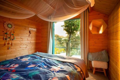 a bedroom with a bed in a room with a window at Tui Ridge Eco Cabins in Aongatete
