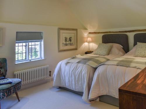 a bedroom with two beds and a chair and a window at Chapel Cottage, in Holmbury Saint Mary