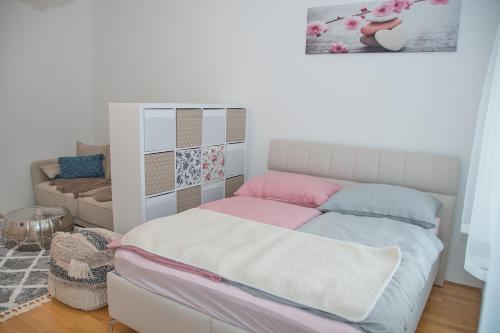 een kleine slaapkamer met een bed met roze en blauwe kussens bij White Lotus Apartment in Wenen