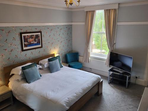 um quarto com uma cama grande e uma televisão em St George's Guest House em York