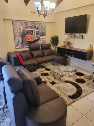 a living room with a couch and a tv at ALBATROSSWAYS LODGE in Sandton