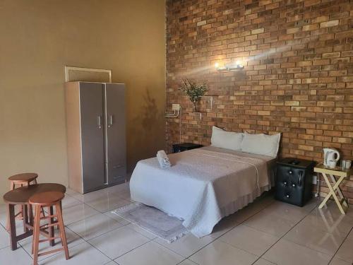 a bedroom with a bed and a brick wall at ALBATROSSWAYS LODGE in Sandton
