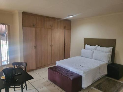 a bedroom with a bed and a chair and a desk at ALBATROSSWAYS LODGE in Sandton