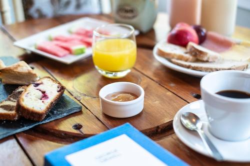 Una mesa de madera con alimentos para el desayuno y una taza de café. en Atelier Hotel de Charme, en Villa General Belgrano