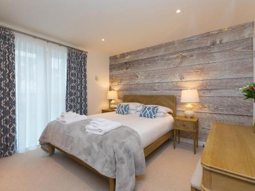 1 dormitorio con 1 cama y pared de madera en Far Cliffs, en St Ives