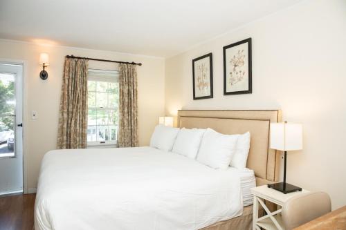 a bedroom with a white bed and a window at Three Village Inn in Stony Brook