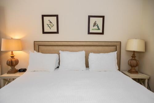 a bedroom with a white bed with two lamps at Three Village Inn in Stony Brook