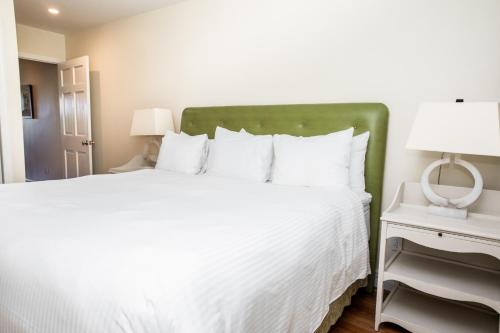 a bedroom with a large white bed with a green headboard at Three Village Inn in Stony Brook