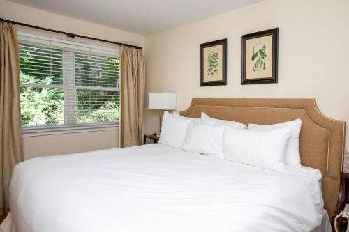 a bedroom with a white bed and a window at Three Village Inn in Stony Brook