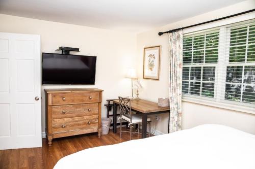 a bedroom with a television on a dresser and a desk at Three Village Inn in Stony Brook