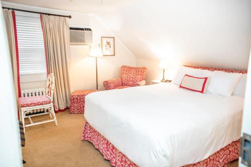 a bedroom with a large white bed and a chair at Three Village Inn in Stony Brook